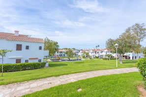 Un barrio residencial con edificios blancos, un sendero pavimentado y un césped bien cuidado.