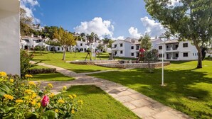 Zona residencial con casas blancas, un sendero pavimentado y un parque infantil.