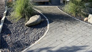 A modern house with a stone facade, a dark front door, and a paved driveway.