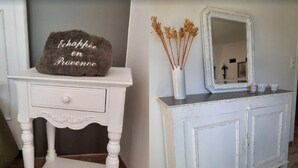 A white dresser with a mirror and a vase with dried plants. A decorative stone with the phrase "Echappé en Provence" is placed on a small table beside the dresser.