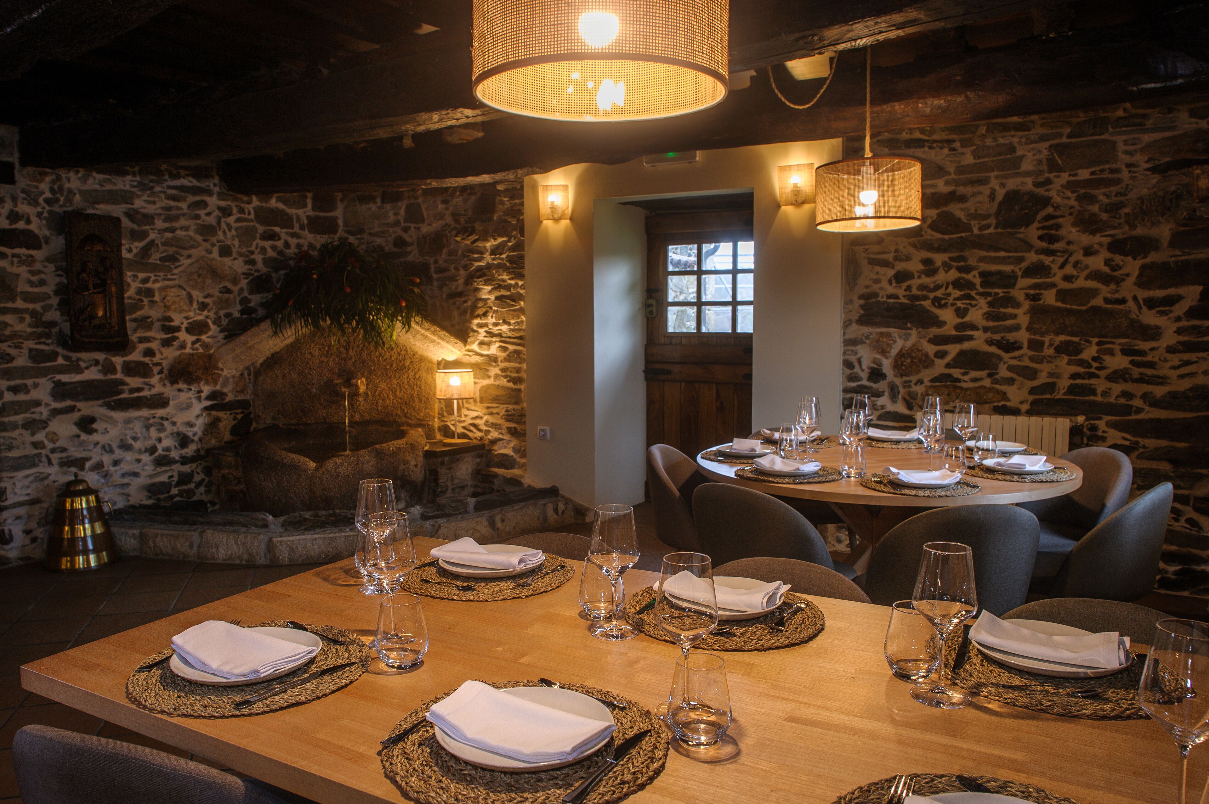 Un restaurante con paredes de piedra, mesas de madera y posavasos tejidos.