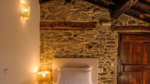 Een bed in een kamer met een stenen muur en een houten deur.