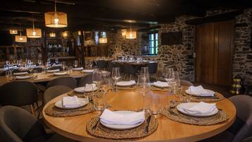 Un restaurant avec des tables rondes dressées pour le dîner, agrémentées de sets de table en fibres tressées, de serviettes blanches et de verres transparents.