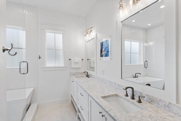 A modern bathroom with a large mirror, two sinks, and a shower.