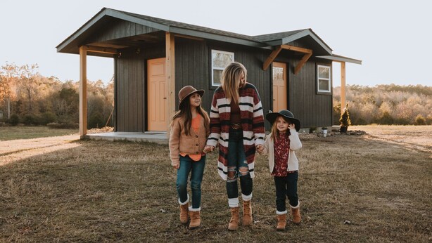 A family standing in front of a wooden house with a porch. - Luxury Glamping tent in Ouachita Mountains (Mena)