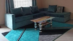 A living room with a sectional sofa, a coffee table, and a patterned rug. - Serene 2 bedroom apartment in the heart of Nakuru (Nakuru)