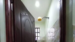 A narrow hallway with a wooden door leading to a bathroom with a shower and a pink mat on the floor. - Serene 2 bedroom apartment in the heart of Nakuru (Nakuru)
