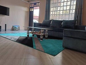 A living room with a sofa, a coffee table, a TV, and a painting on the wall.