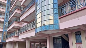 A multi-story residential building with balconies, a car parked in front, and a staircase leading to the entrance. - Serene 2 bedroom apartment in the heart of Nakuru (Nakuru)