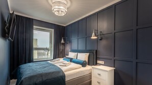 A modern bedroom with a large bed, a bedside table, and a window.