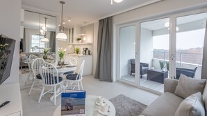 A modern apartment with a dining area, kitchen, and balcony.