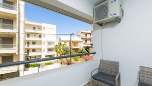 A balcony with a view of neighboring buildings, an air conditioning unit, and a wicker chair. - Cozy apartment in the heart of Rethymno town, nr. 1 (Rethymno)