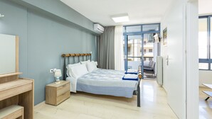 A bedroom with a bed, bedside table, lamp, and a view of the outside. - Cozy apartment in the heart of Rethymno town, nr. 1 (Rethymno)