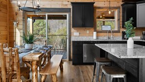 Une cabane en bois dotée d’une cuisine avec des comptoirs en granit, des armoires noires et un lave-vaisselle encastré.