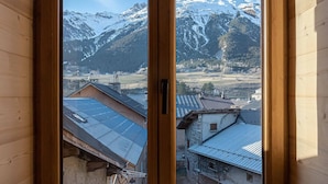 A wooden room with a large window offering a view of snow-capped mountains and a village below. - Le Temps Suspendu "Chardon Bleu" - Relaxation Stay - Apartment 8 people (TERMIGNON)