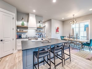 A modern kitchen with a large island, bar stools, and a dining area with a table and chairs.