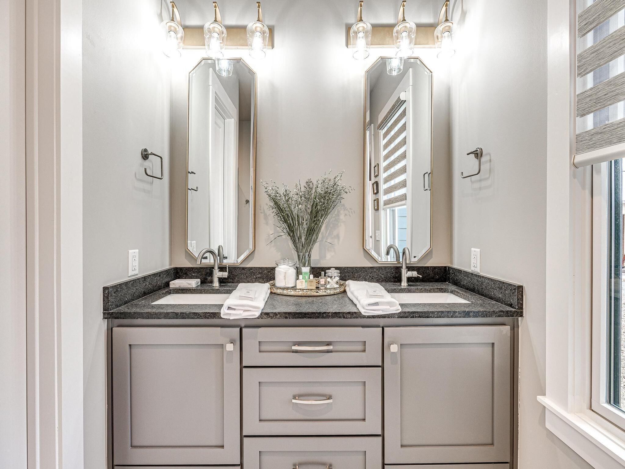 A bathroom with two sinks, a mirror, and a vanity with drawers.
