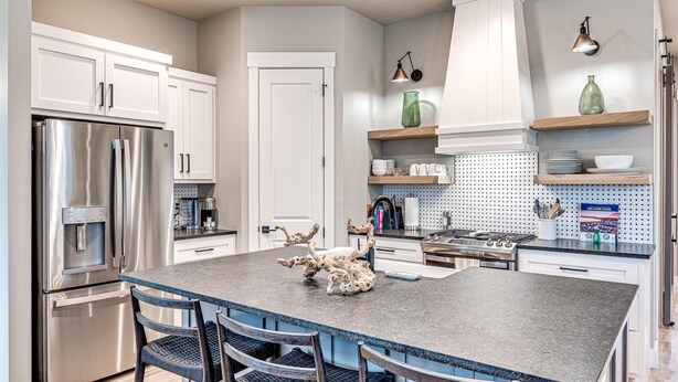 A modern kitchen with stainless steel appliances, a central island with chairs, and decorative items.