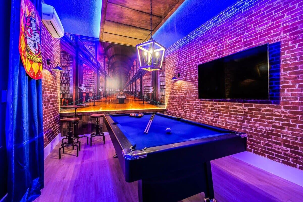 A billiards table in a room with brick walls and a neon sign.