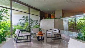 Um espaço moderno em ambientes internos com grandes janelas, área de estar com mesa redonda e diversas plantas.