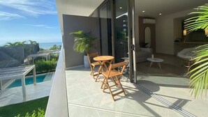 Uma varanda com piscina, móveis de madeira e vista para o oceano.