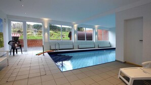 A swimming pool with a bench, a chair, and a small table. - Appartement in Westerland auf Sylt (Westerland)