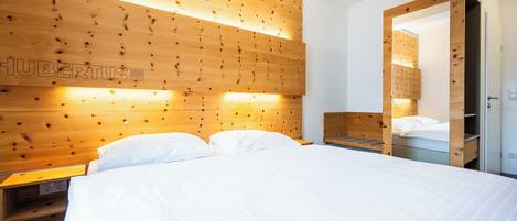 A hotel room with a wooden headboard, a bed with white linens, a bedside table, and a wardrobe.