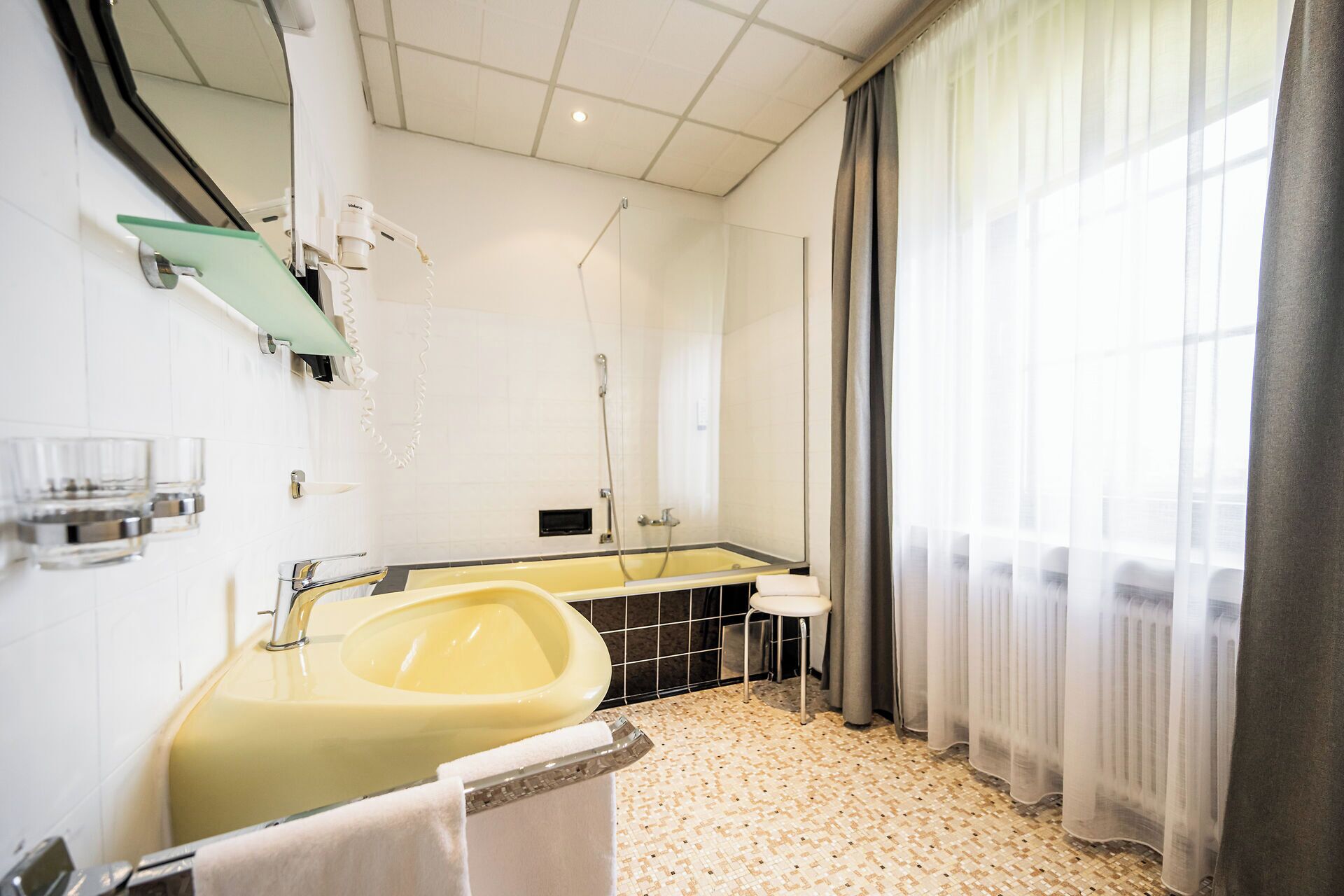 A modern bathroom with a yellow sink, a mirror, and a shower area.