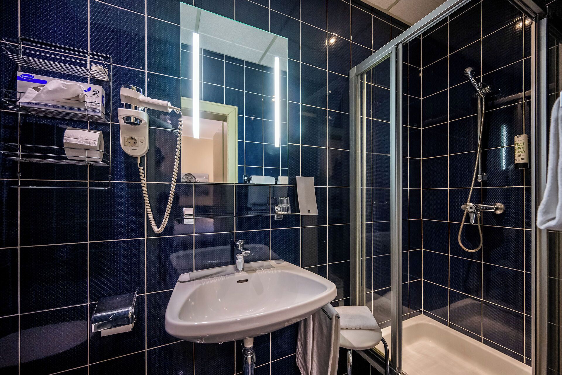 Un bagno moderno con cabina doccia in vetro, lavandino bianco e specchio.