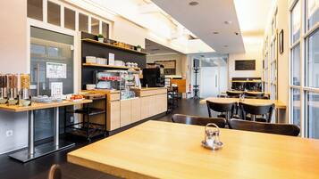 A modern restaurant interior with a counter, seating area, and kitchen.