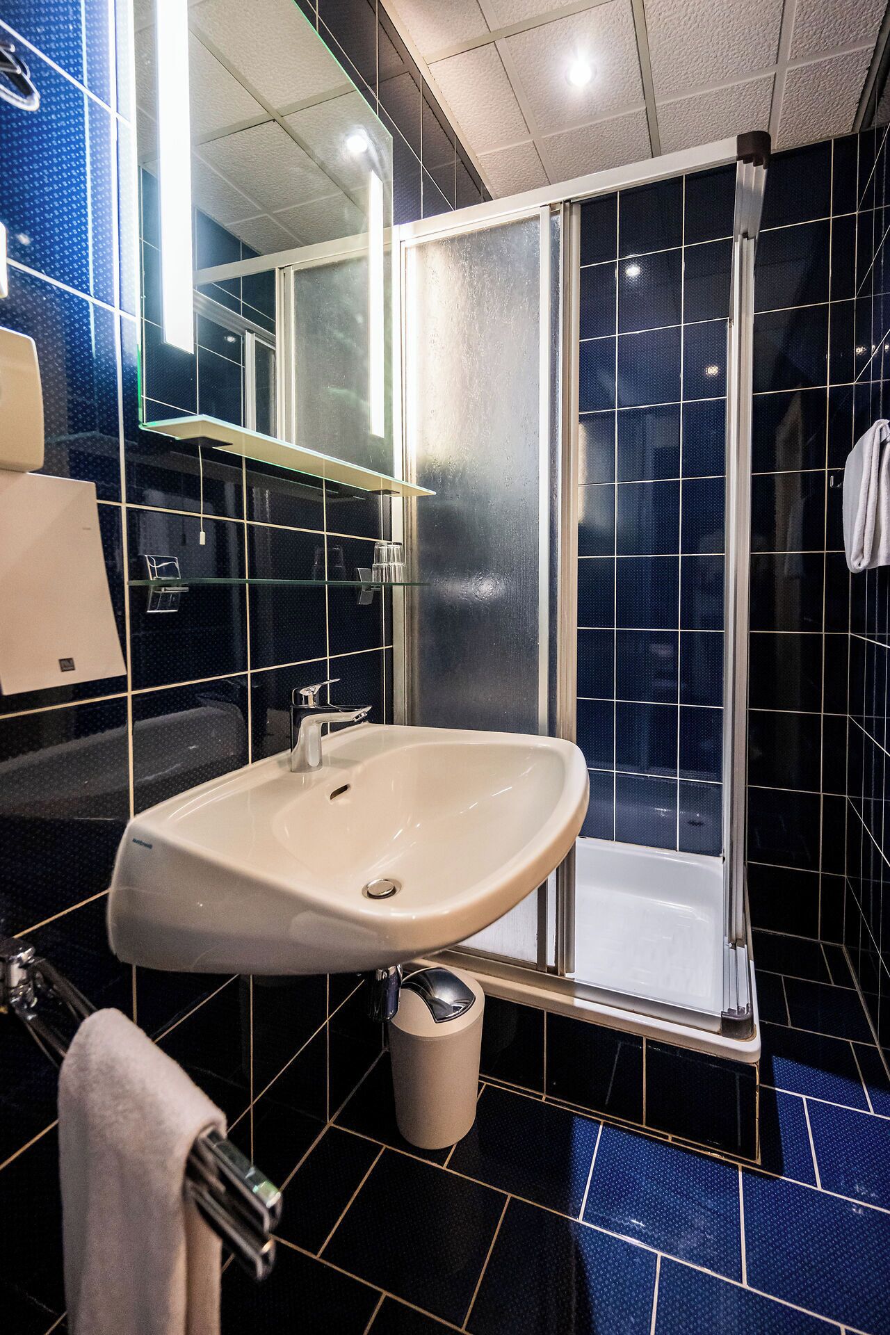 Un baño con lavamanos, espejo y ducha.