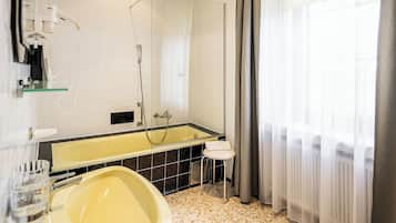 A modern bathroom with a large bathtub, a mirror, and a shower.