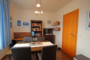 Un comedor con una mesa, sillas, una estantería, un televisor y una puerta.