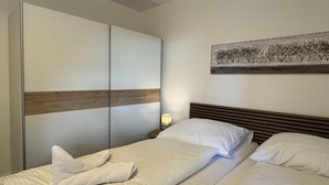 Ein Schlafzimmer mit Bett, Nachttisch, Wandbild und Kleiderschrank.
