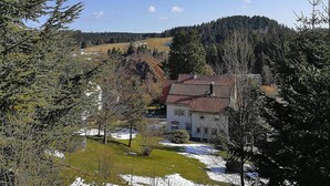 Ein Haus mit rotem Ziegeldach, umgeben von Bäumen und einer hügeligen Landschaft.