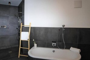 Ein modernes Badezimmer mit Badewanne, Dusche und einer Holzleiter.