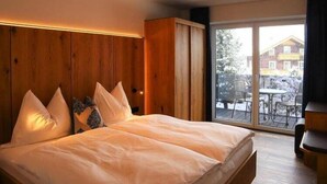 Un dormitorio con una cama grande, cabecera de madera y vistas a un paisaje nevado a través de una puerta corrediza de vidrio.