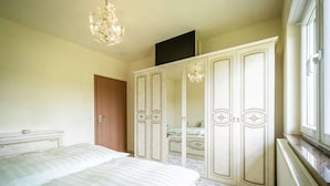 A bedroom with a bed, a wardrobe, a mirror, and a chandelier.