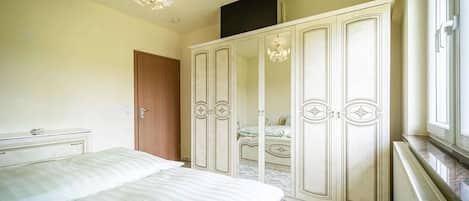 Un dormitorio con cama, armario, espejo y candelabro.