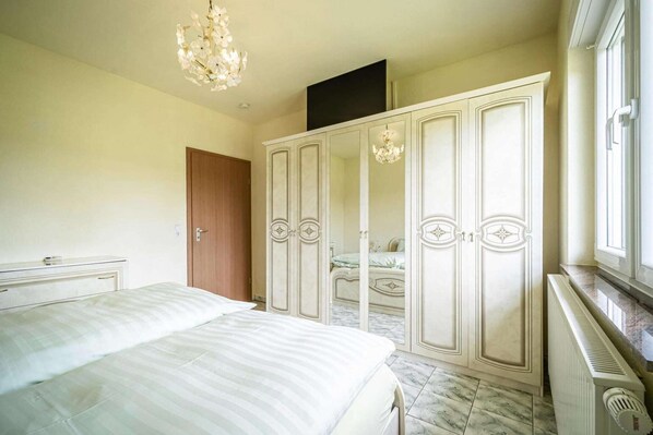 A bedroom with a bed, a wardrobe, a mirror, and a chandelier.