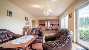A spacious living area with leather sofas, a wooden coffee table, and a chandelier.