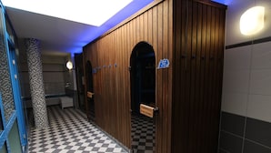 A public restroom with wooden partitions, a checkered floor, and a blue ceiling light.