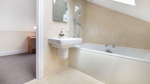 Ein modernes Badezimmer mit einer freistehenden Badewanne, einem wandmontierten Waschbecken und einem großen Spiegel.