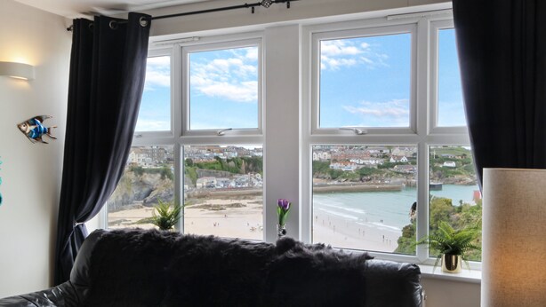 Ein Zimmer mit großem Fenster mit Blick auf Strand und Stadt.