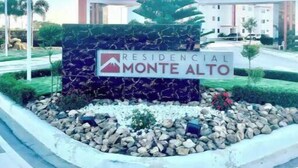 Une enseigne indiquant « Residencial Monte Alto », avec un immeuble moderne en arrière-plan.