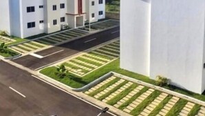 Un complexe résidentiel moderne composé de plusieurs bâtiments blancs, une rue principale et des espaces verts aménagés.
