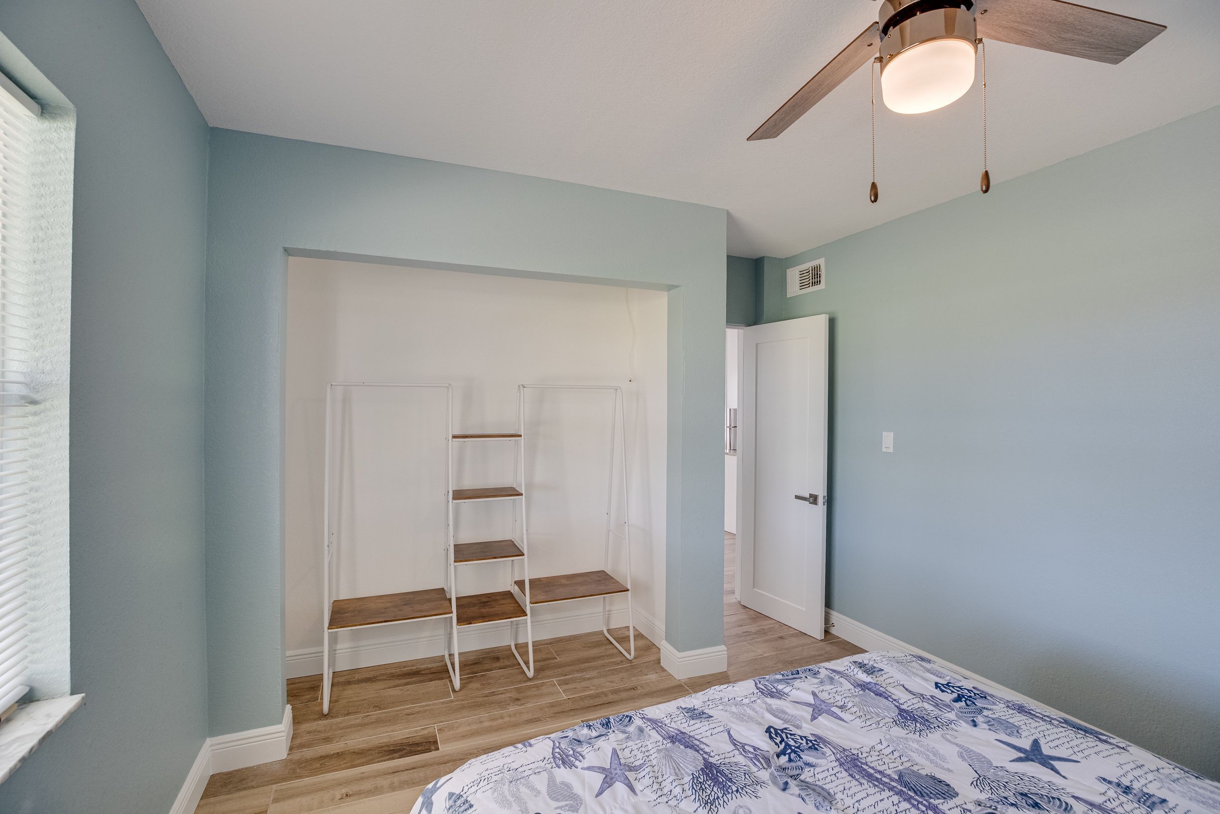 Een slaapkamer met een bed, een plafondventilator, een kledingkast en een ladder.