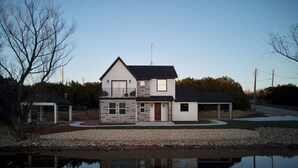 Ein zweistöckiges Haus mit Naturstein-Fassade, Garage und überdachter Terrasse.