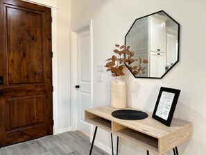 Enter a serene space with a door leading to a room, a console table, and a large mirror above.