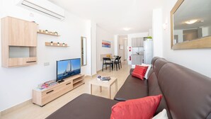 A modern living room with a flat-screen TV, a brown sofa, a coffee table, and a dining area with a table and chairs. - Sea Bliss Penthouse with two terraces enjoying side seaviews by Gatewaysmalta (St. Paul's Bay)